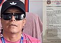 Rajkumar Shakya, Chief Administrative Officer, sitting in front of a Chulachuli Gaupalika office backdrop, looking serious while wearing a pink shirt, black Adidas cap, and sunglasses, with a letter in Nepali on the right side of the image.